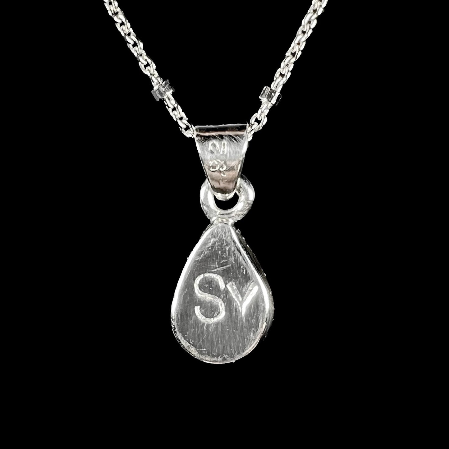 A pear shaped black opal necklace set in sterling silver.  The opal vividly flashes every color of the rainbow.