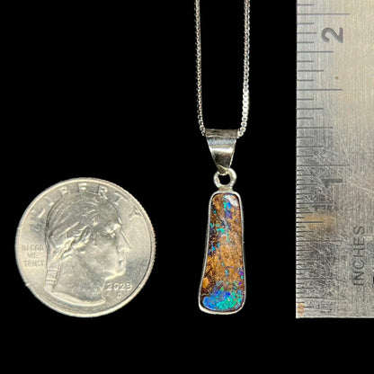 A sterling silver necklace bezel set with a natural Australian boulder opal stone.  The stone shines colors of blue, green, and purple.