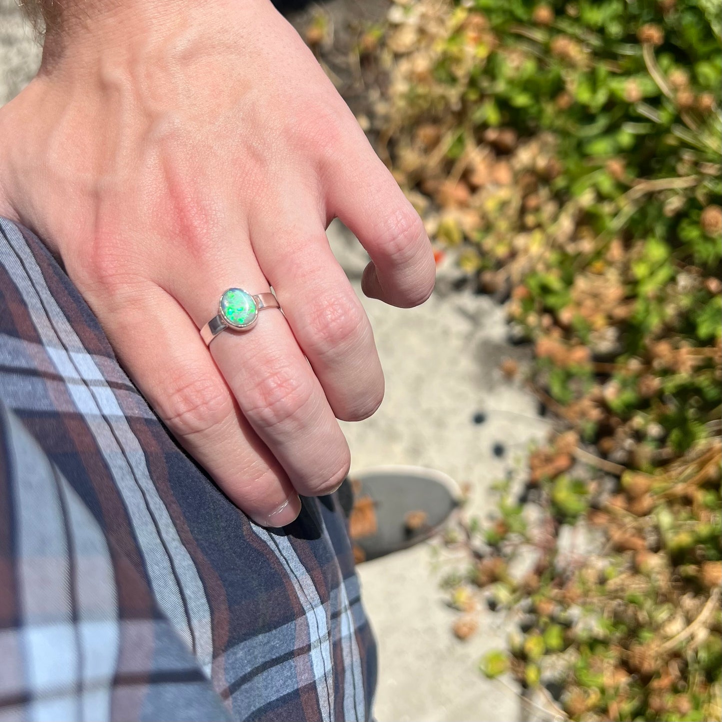 Person resting hand on their hip in sunlight while wearing a simple sterling silver Australian opal solitaire ring.