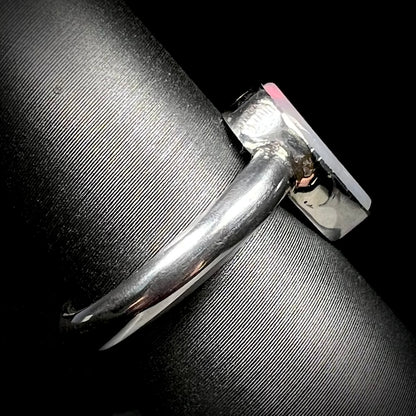 Side profile view of a simple sterling silver opal ring on a ring display, its polished shank in focus.