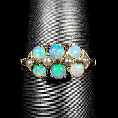 Close-up of 9k gold Victorian six-stone ring set with round Australian opals and pearl accents, shown on ring display