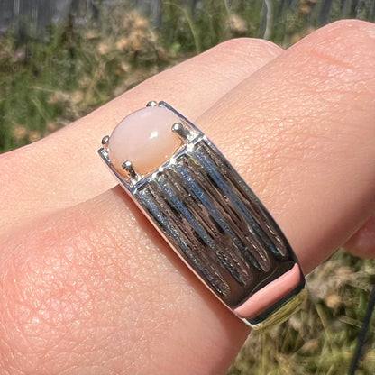 Size 12 sterling silver pink Peruvian opal ring worn on finger in natural sunlight