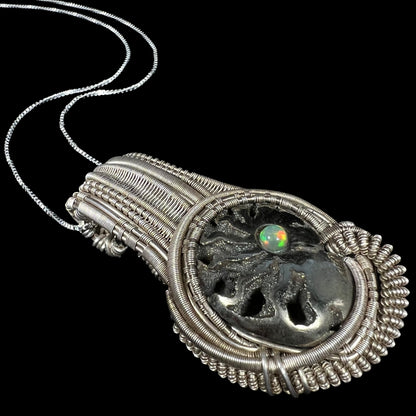 Angled close-up of men's silver wire wrapped pendant set with pyritized ammonite snail fossil and colorful Ethiopian opal accent.