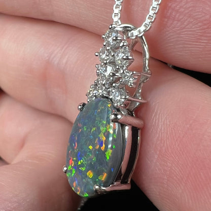 Side macro view of natural black opal pendant with solid composition and N3 body tone, held in hand.