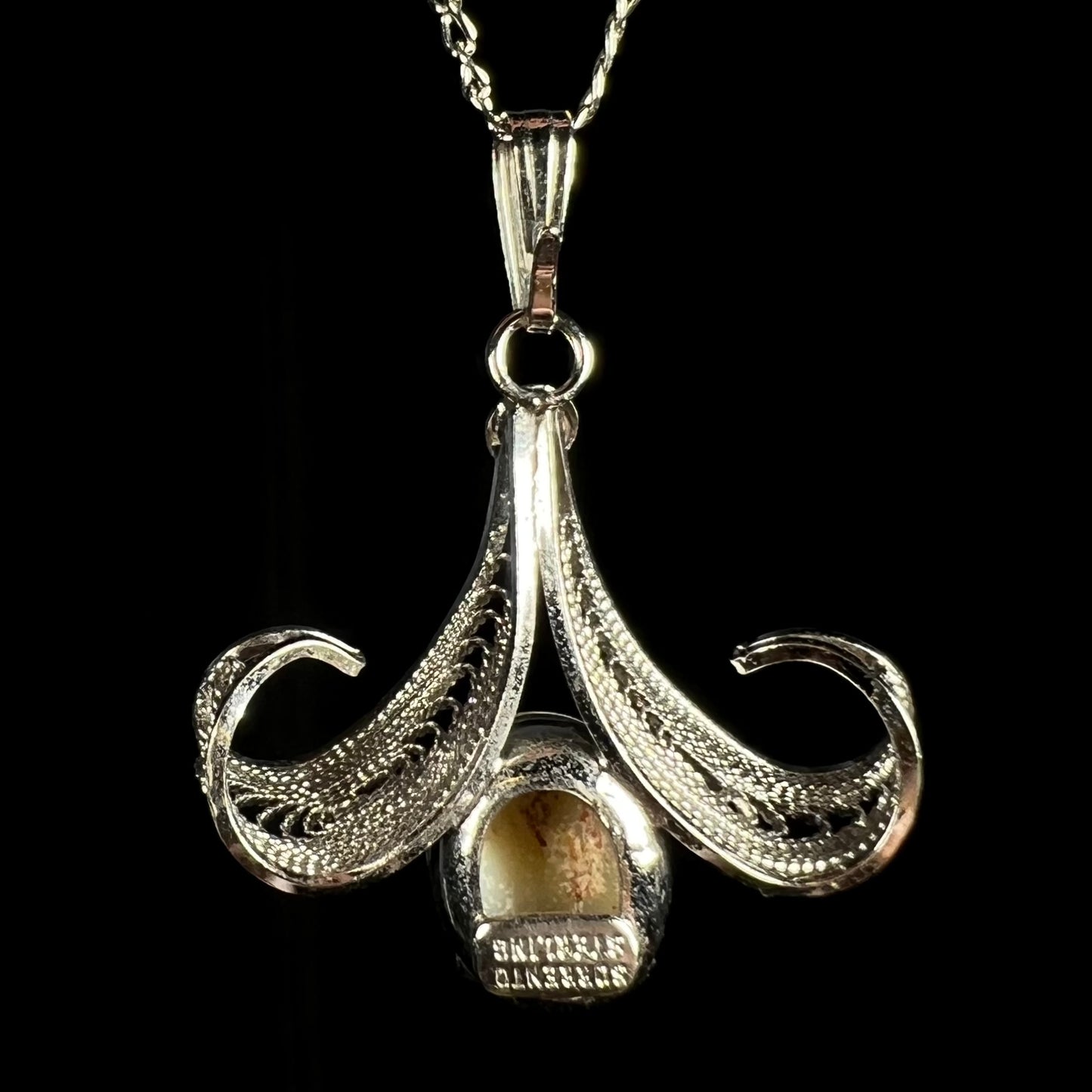 Back side of a Sorrento brand sterling silver opal pendant, shown against a black background.