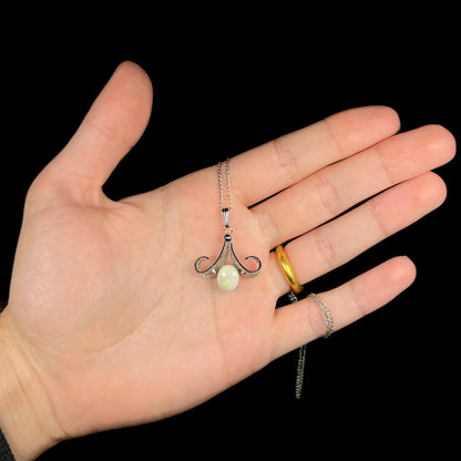 A Sorrento brand sterling silver Australian white opal pendant shown in a hand against a black background.