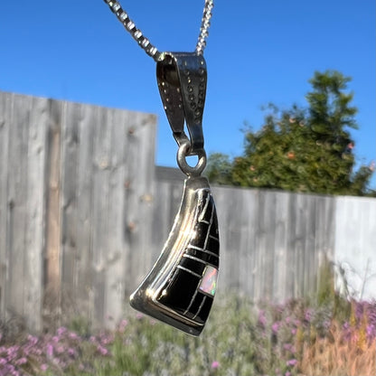 Opposite angled side view of Southwest-style silver opal and onyx inlay necklace outside, showing opal color play in natural light.