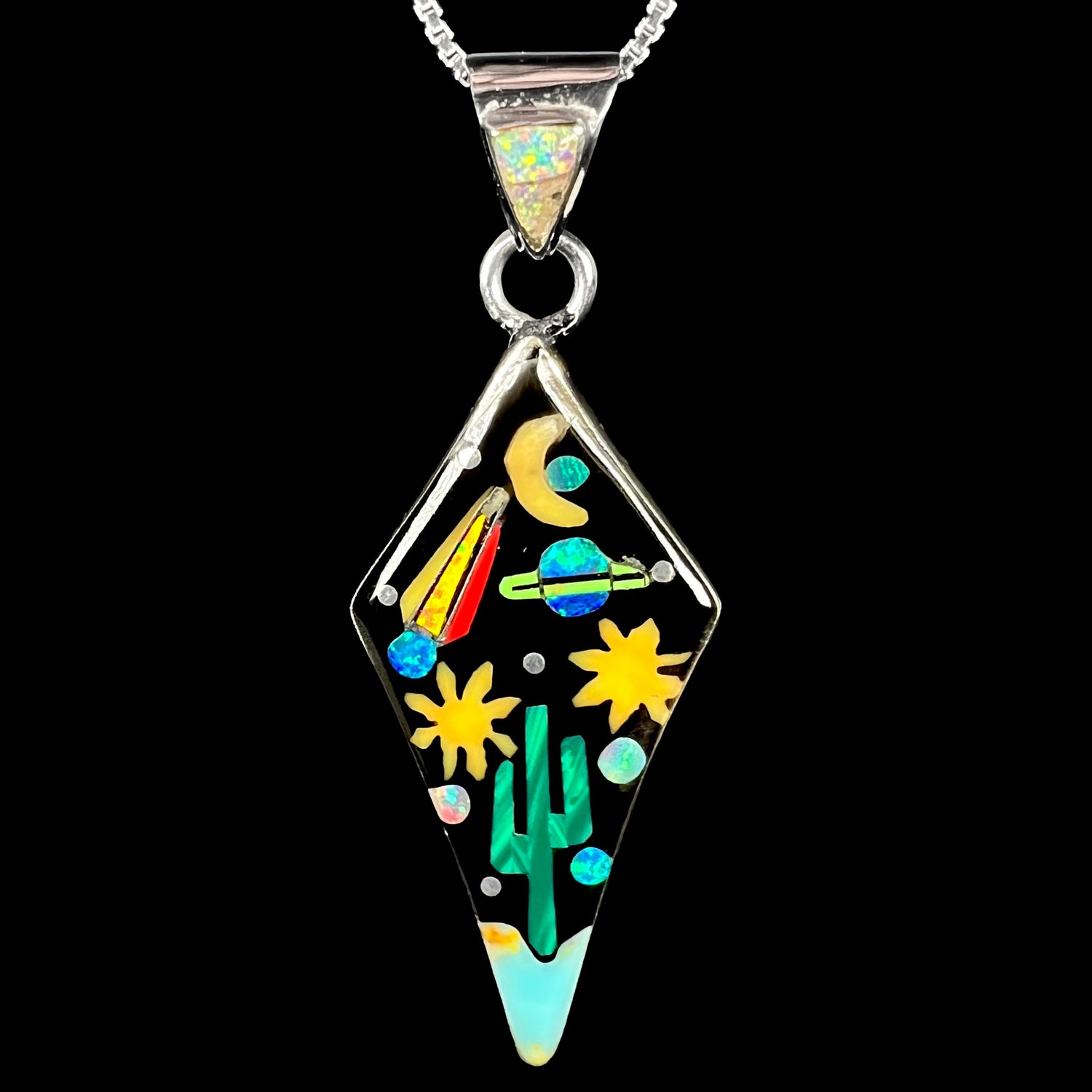 Southwest-style sterling silver opal, onyx, and malachite inlay pendant depicting motif of outer-space over desert floor, shown against black backdrop.
