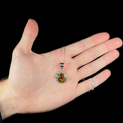 Hand holding a Southwest-style fire agate necklace with leaf and bead design pendant on box chain.