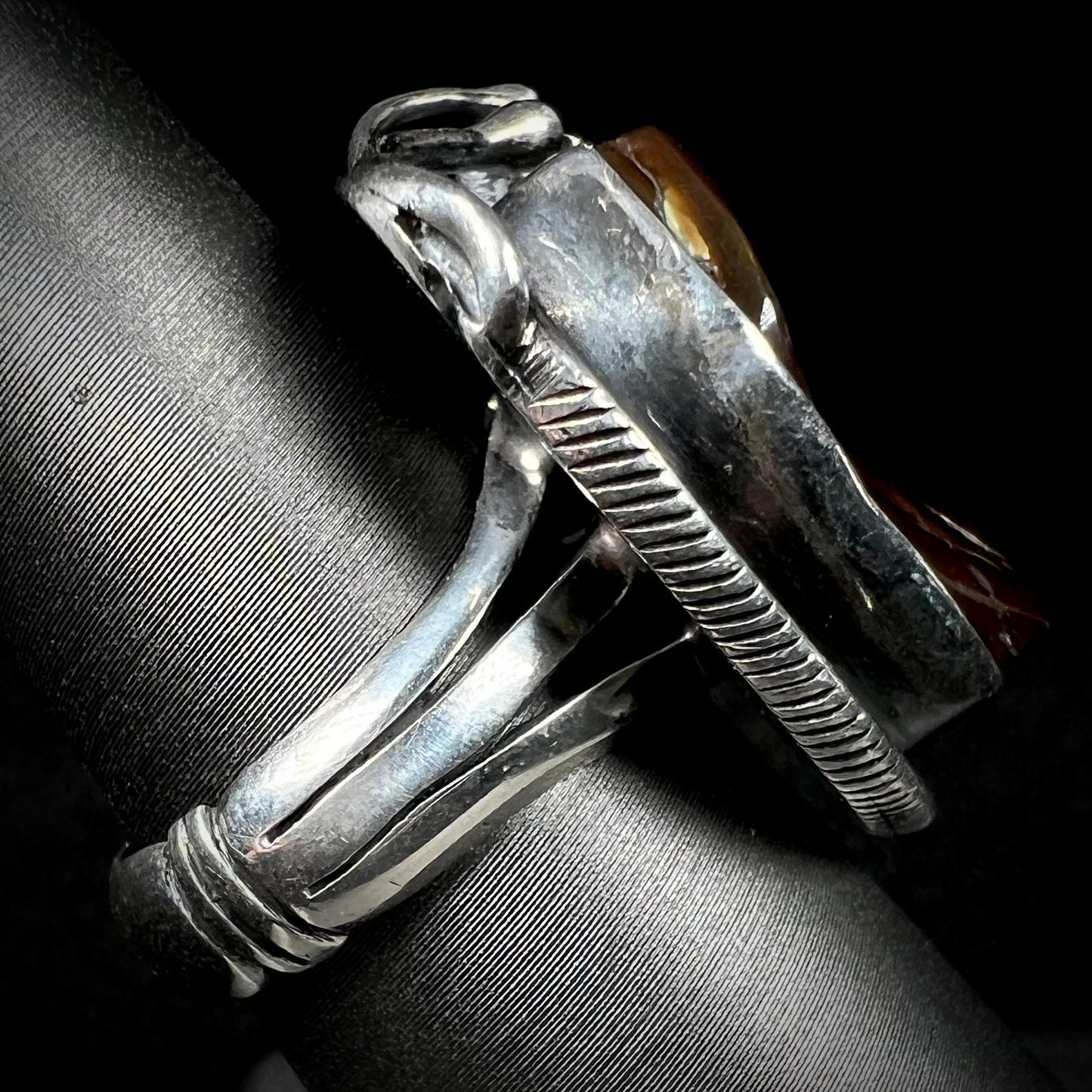 A men's silver, Southwest-style fire agate ring shown from the side view.