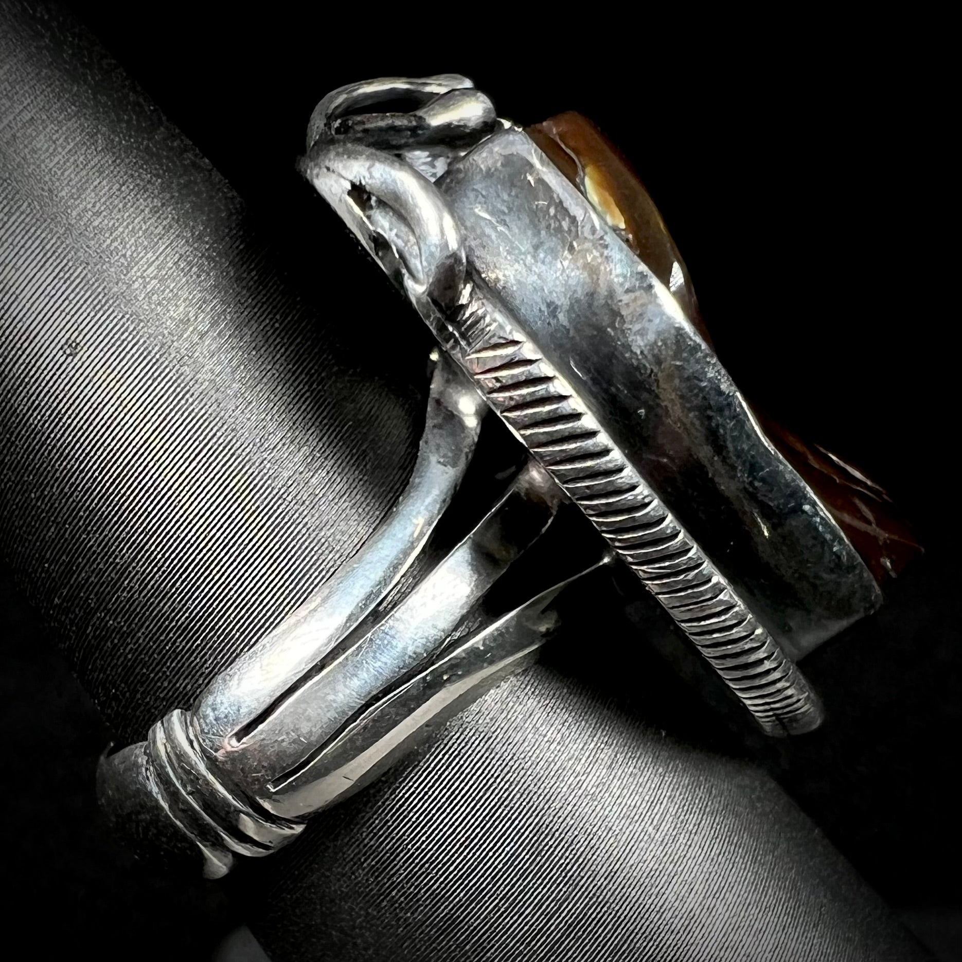 A men's silver, Southwest-style fire agate ring shown from the side view.