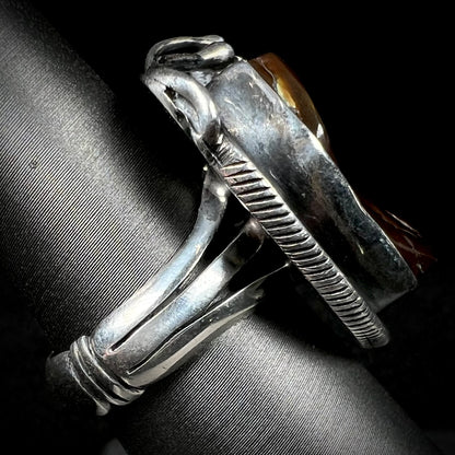 A men's silver, Southwest-style fire agate ring shown from the side view.