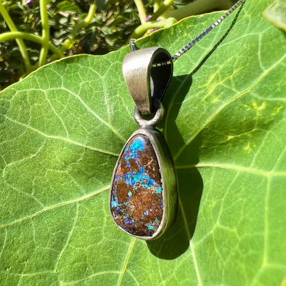 A handmade, satin finish sterling silver pendant set with a drop shaped boulder opal stone.