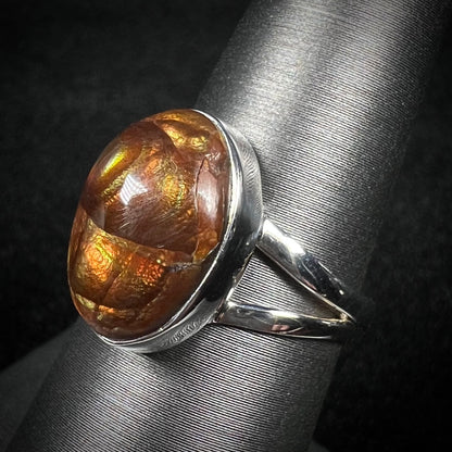 Split shank fire agate ring shown from an angled view against dark backdrop.  Fire agate shows crack inclusion.