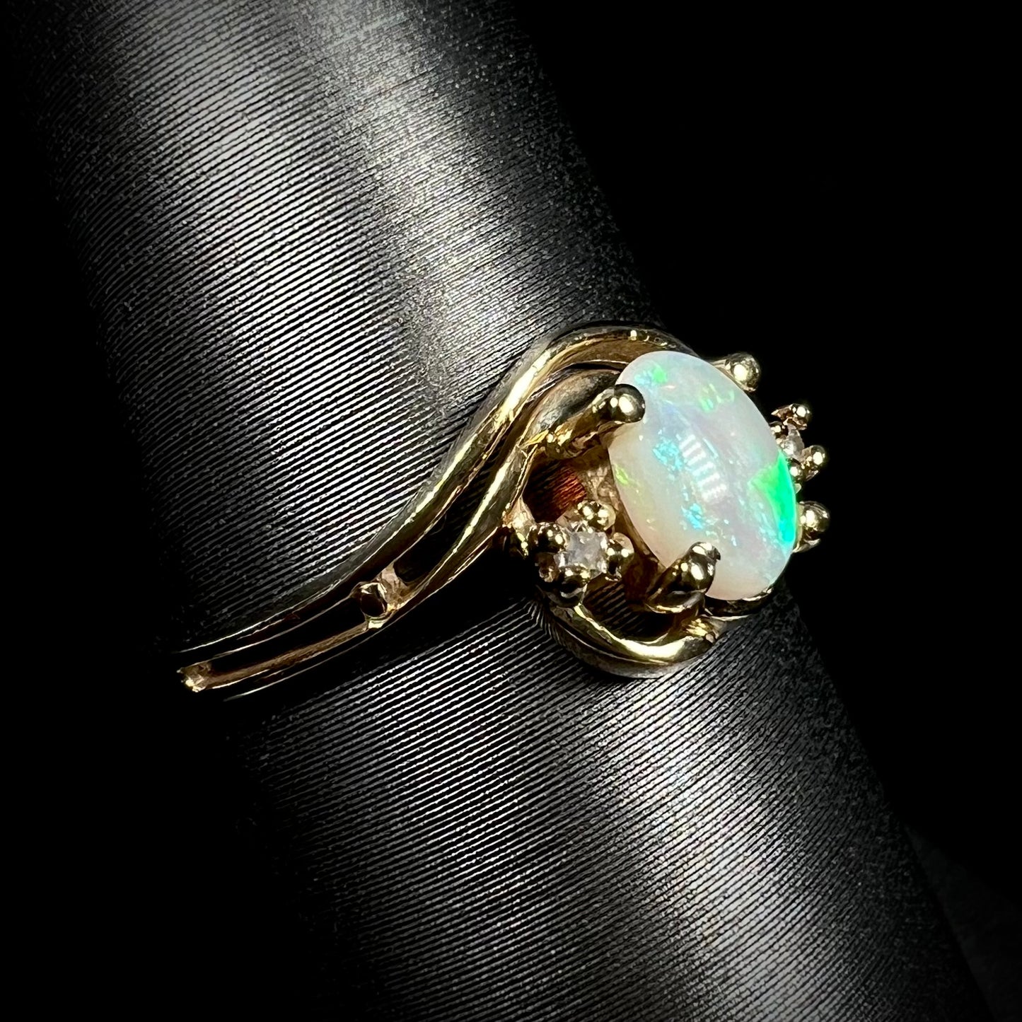 Angled close-up of a yellow gold Australian opal and diamond ring with a split shank design.