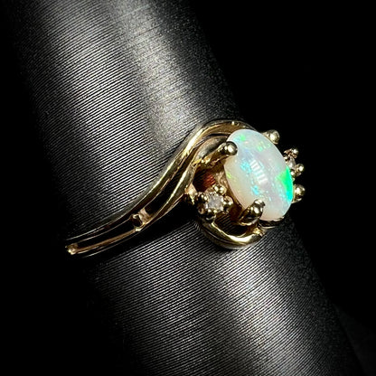 Angled close-up of a yellow gold Australian opal and diamond ring with a split shank design.