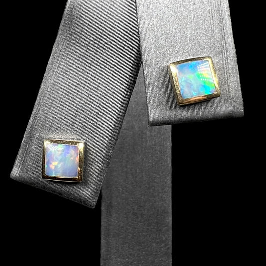 Pair of square shaped opal stud earrings in 14k gold on earring display