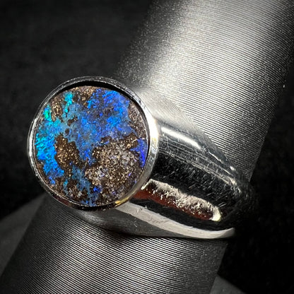 A stainless steel men's Australian boulder opal ring with blue color play shown on a ring display from an angle.
