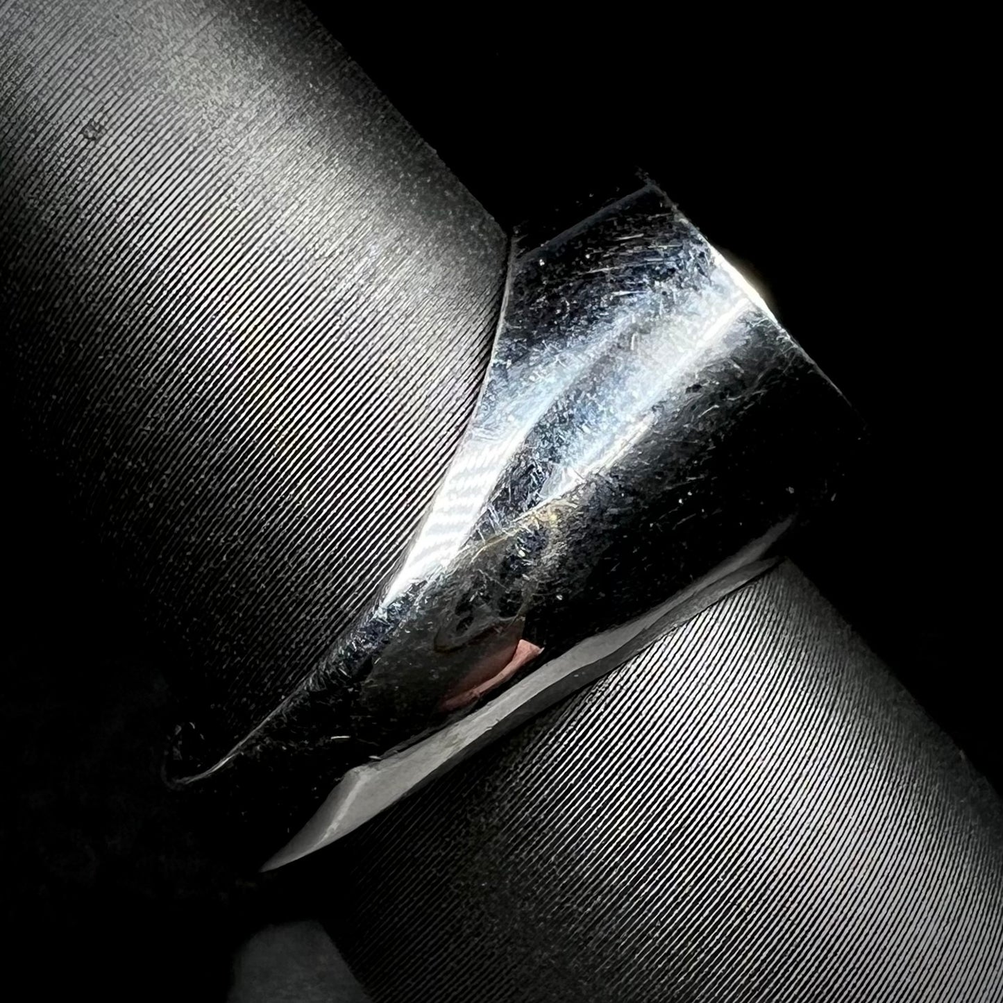 Side view of an estate stainless steel gypsy mount style men's ring on a ring display against a black background.