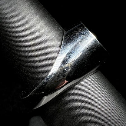 Side view of an estate stainless steel gypsy mount style men's ring on a ring display against a black background.