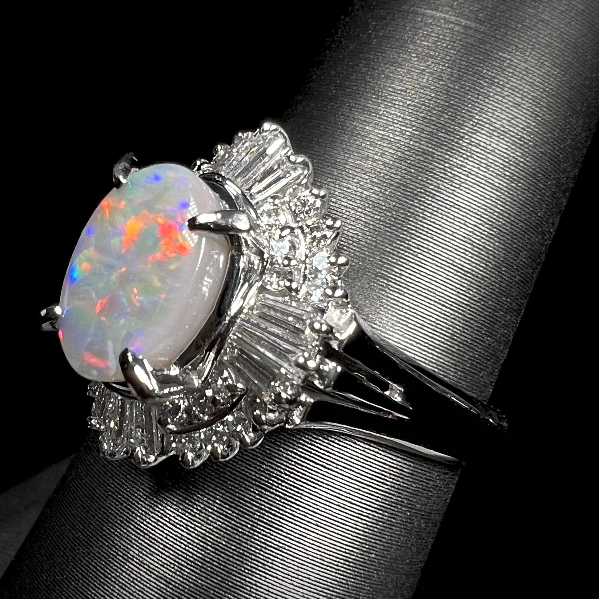 Angled view of a statement platinum opal and diamond ring, featuring a 1.47ct Lightning Ridge semi-black opal with red and blue fire.