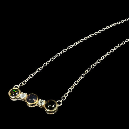 A three-stone black Ethiopian opal and white topaz necklace in two-tone sterling silver.