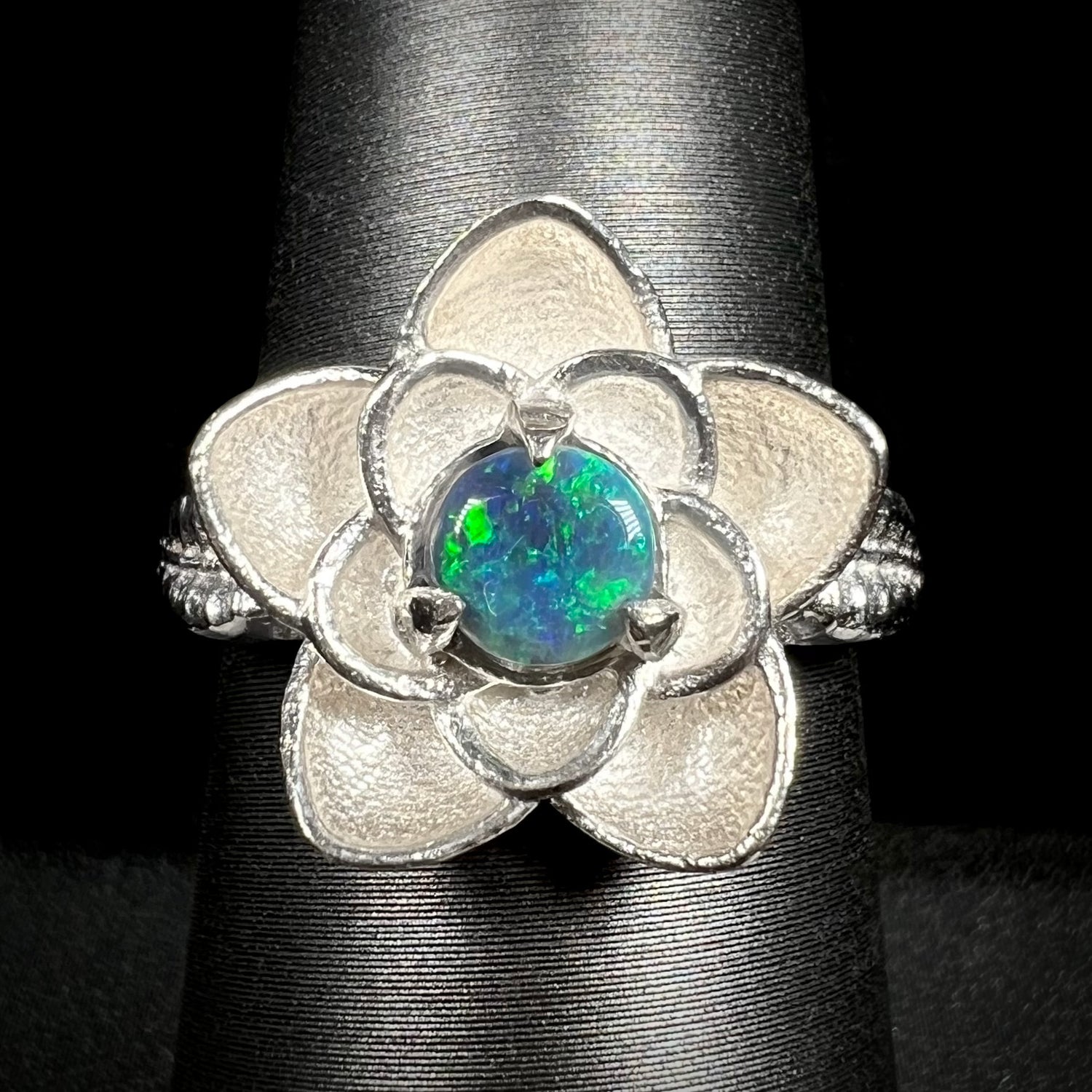 Close-up of sterling silver lotus flower design ring set with round Australian black opal on ring display