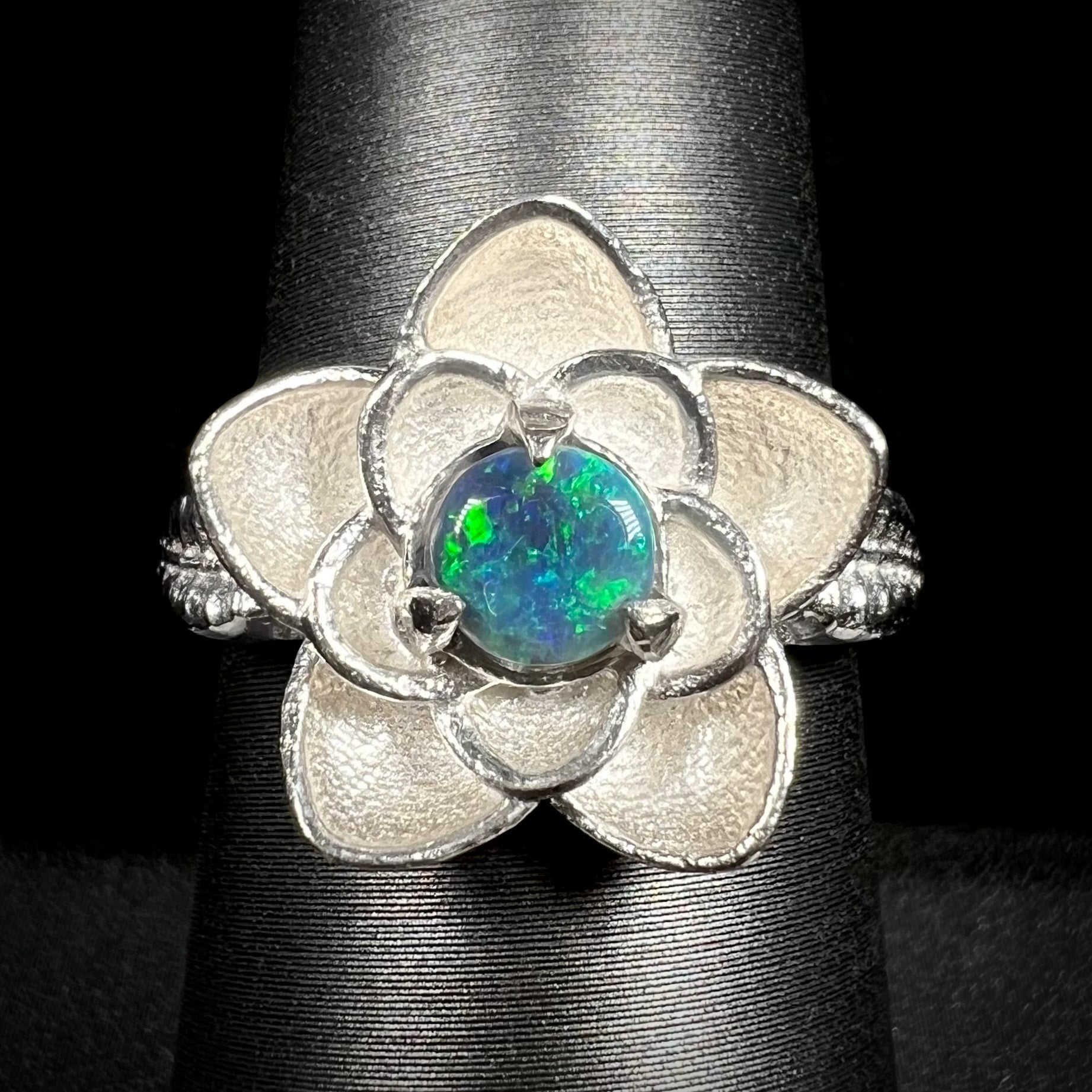 Close-up of sterling silver lotus flower design ring set with round Australian black opal on ring display