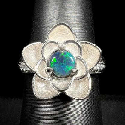 Close-up of sterling silver lotus flower design ring set with round Australian black opal on ring display