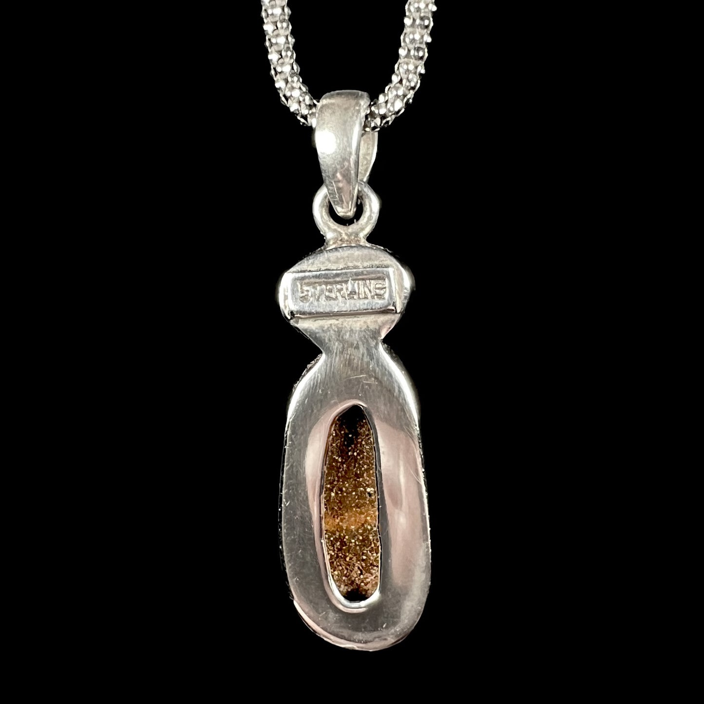 The back of a handmade sterling silver boulder opal necklace, revealing the natural ironstone matrix and ‘STERLING’ stamp on the pendant’s setting.