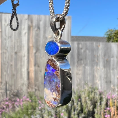 A macro close-up of a sterling silver boulder opal necklace in sunlight, showing its natural ironstone matrix with no visible opal flashes.