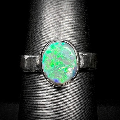 A unisex .999 fine silver Lightning Ridge opal solitaire ring with a bright green flash of color, shown close-up on a ring display against black background.