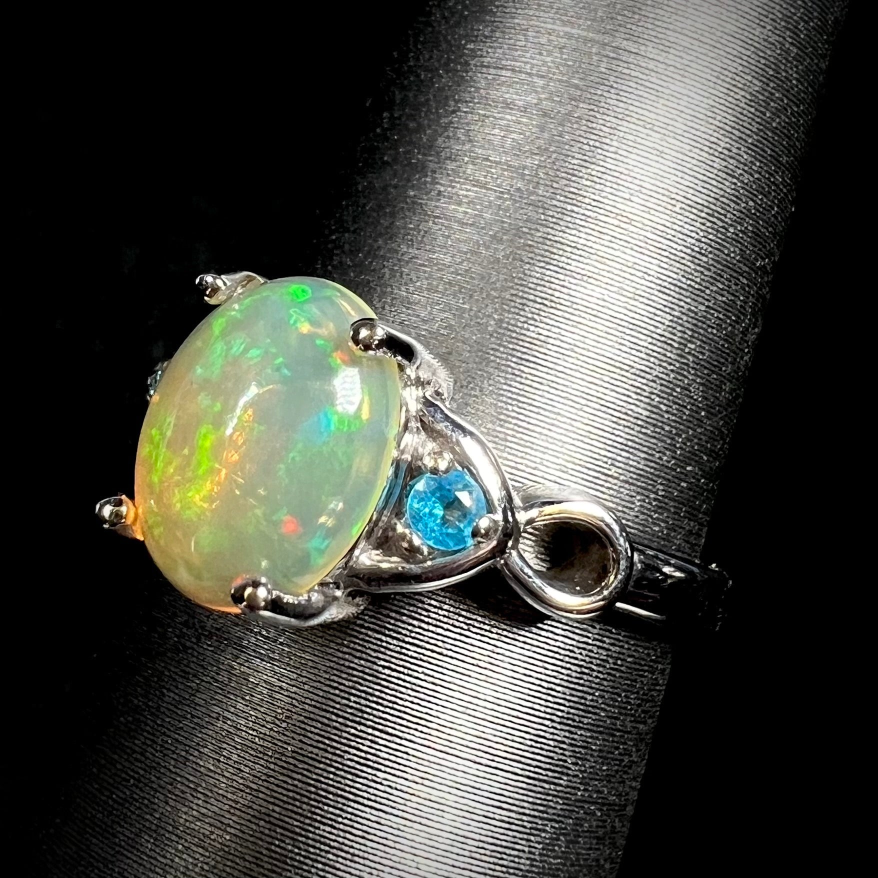 Angled close-up of sterling silver Ethiopian opal and blue apatite ring on ring display