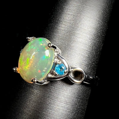Angled close-up of sterling silver Ethiopian opal and blue apatite ring on ring display