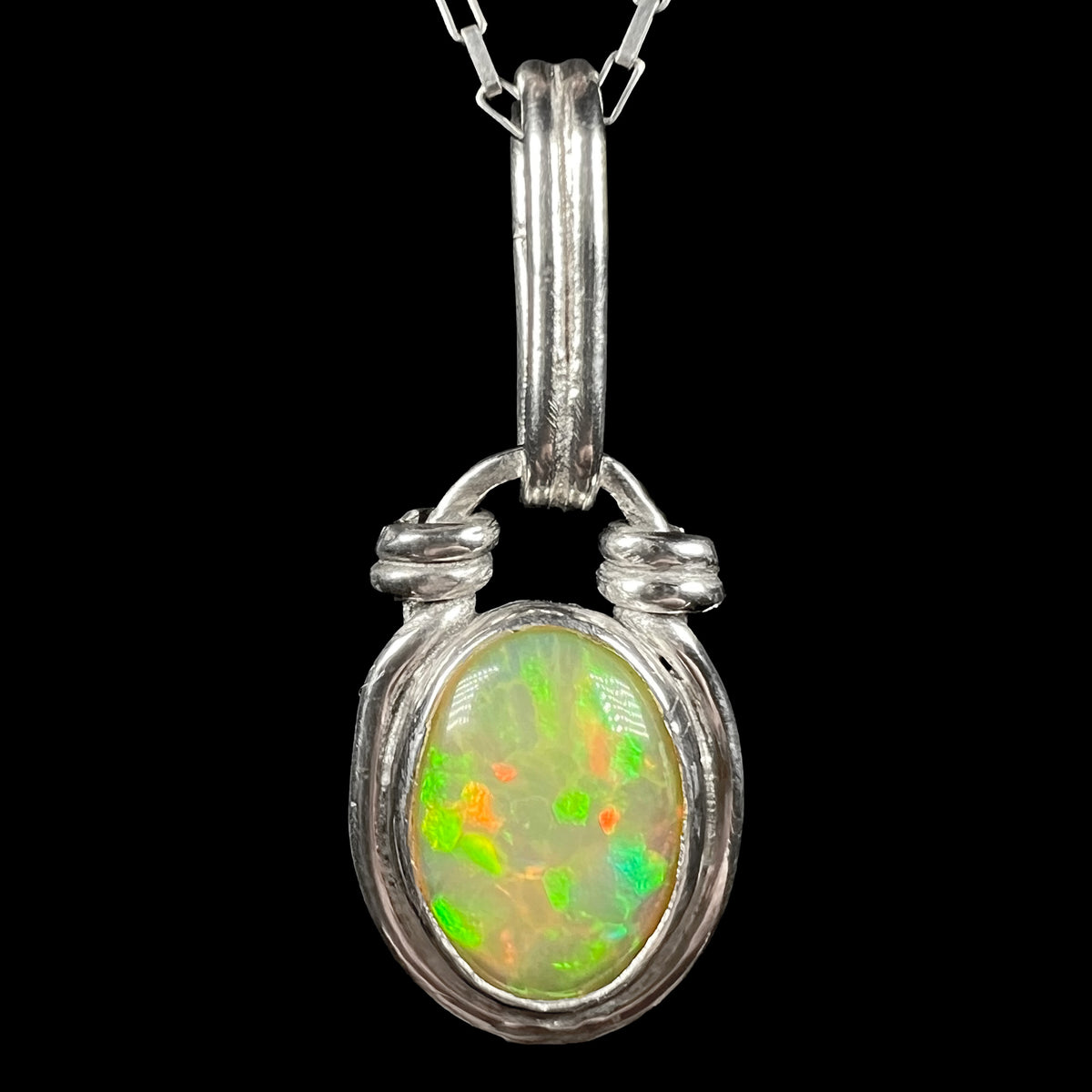 A colorful sterling silver Ethiopian opal pendant shown from the front against a black background.