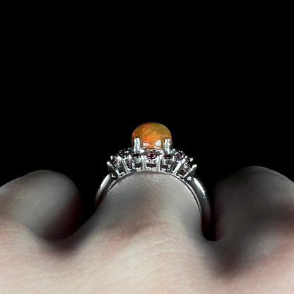 Side profile gallery view of sterling silver ring set with high-domed Ethiopian opal, worn on finger