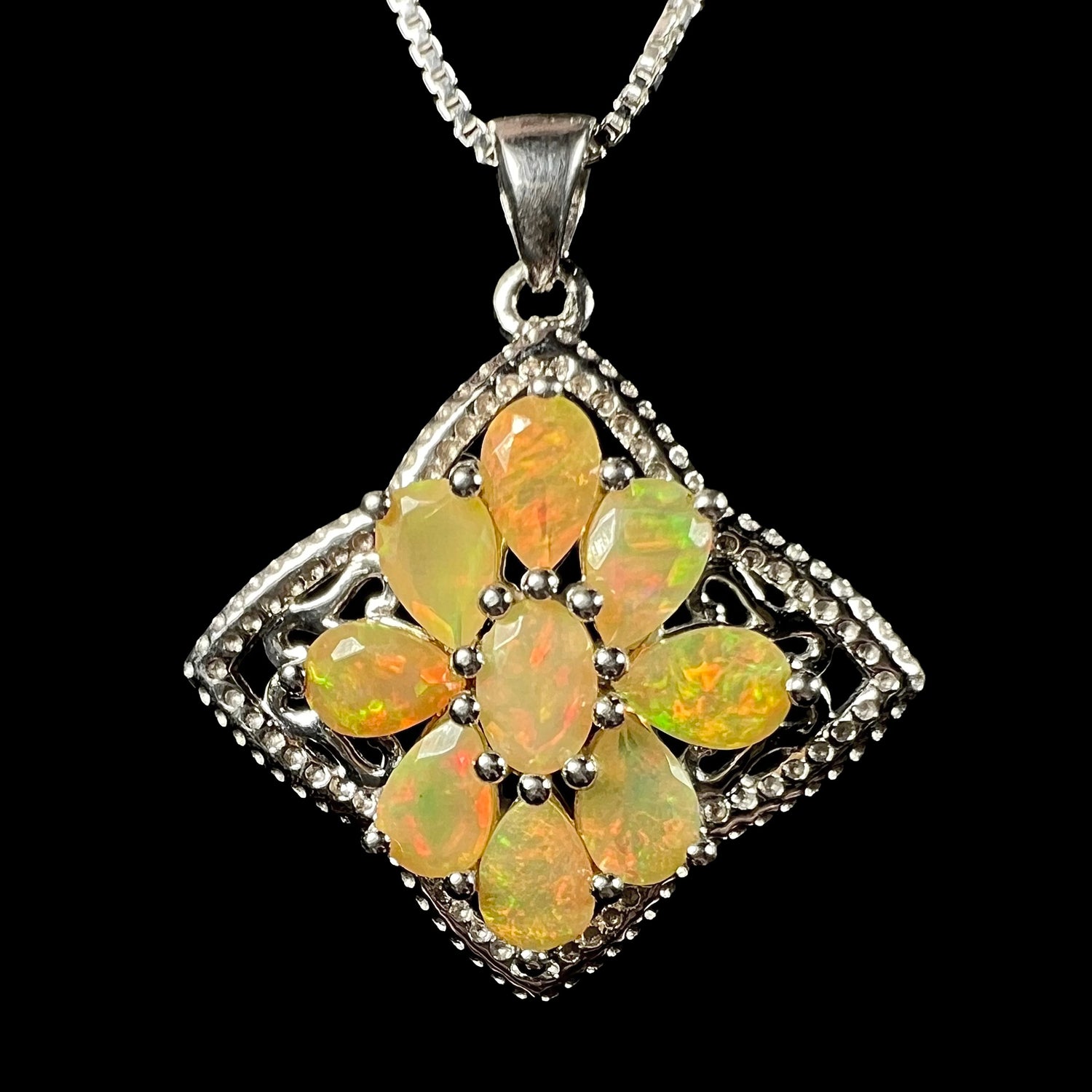 A sterling silver Ethiopian opal cluster star necklace, shown on a chain from the front against a black background.
