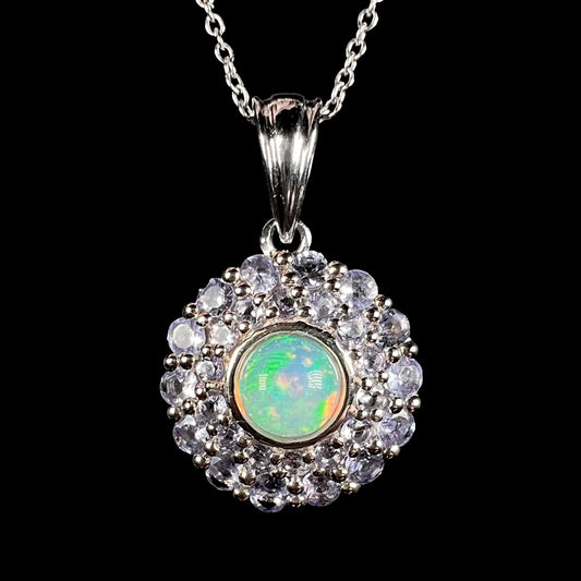 Front close-up of a sterling silver women's pendant set with a round Ethiopian fire opal in the middle of a double halo of light denim blue tanzanites, shown on a silver chain.