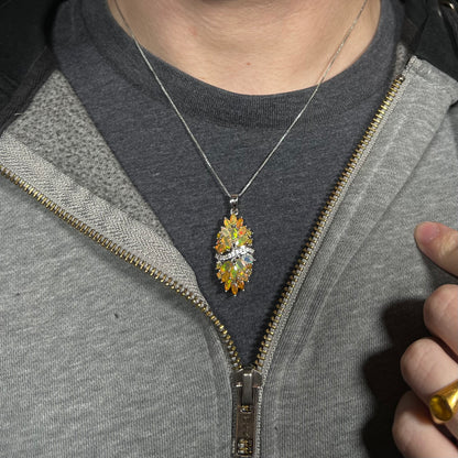 Close-up of a person's neck and chest area wearing a sterling silver Ethiopian opal cluster necklace with white zircon accents against a dark shirt beneath a hoodie.