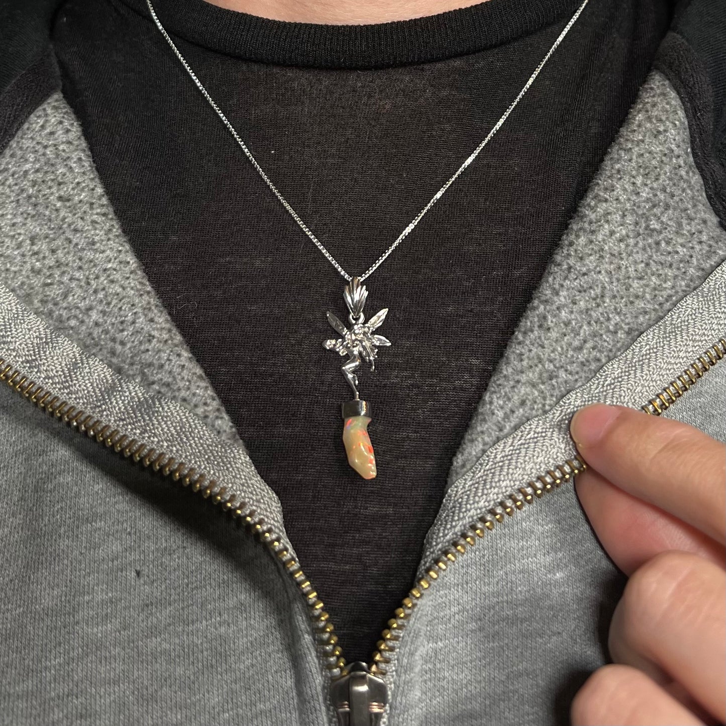 A sterling silver fairy necklace with an Ethiopian fire opal crystal, worn against a dark shirt.