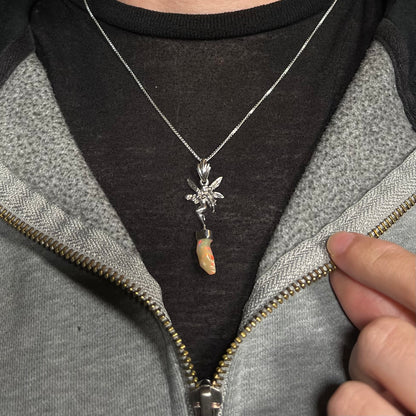 A sterling silver fairy necklace with an Ethiopian fire opal crystal, worn against a dark shirt.