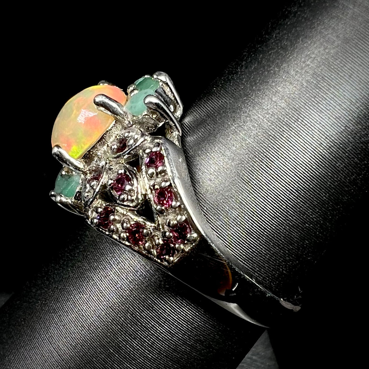 Side view of sterling silver Ethiopian fire opal and rhodolite garnet ring on display showing ring's split-shank design