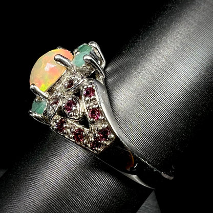 Side view of sterling silver Ethiopian fire opal and rhodolite garnet ring on display showing ring's split-shank design