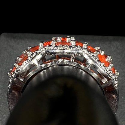 Side gallery profile view of a sterling silver fire opal ring on a ring display.  Part of the gallery is missing a piece, a defect from casting.