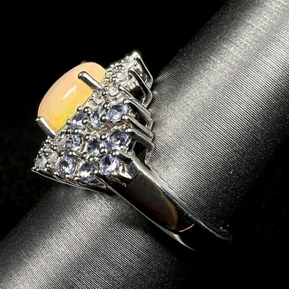 Side view of sterling silver fire opal ring with tanzanite accents, on ring display