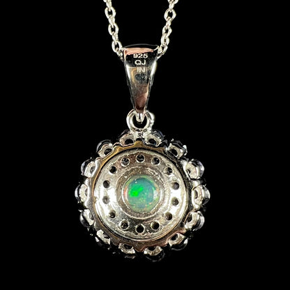 Back side of a round sterling silver pendant on a chain; the back of a green Ethiopian opal is visible, and the pendant's bail is stamped with the hallmarks "925", "QJ", and "IN".
