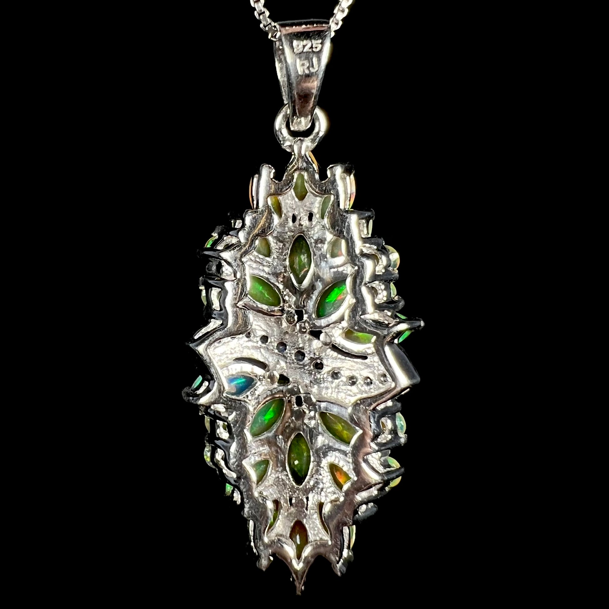 Back side of a sterling silver pendant; the back facets of set marquise cut Ethiopian opals flash green, and the hallmark stamps "925" and "RJ" are seen on the bail.