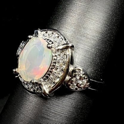 Sterling silver opal ring with CZ-accented halo and heart design on display