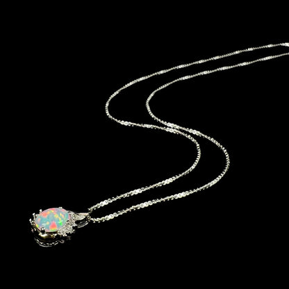 Angled view of a sterling silver lab-created opal and diamond necklace with its chain splayed out on a black background.