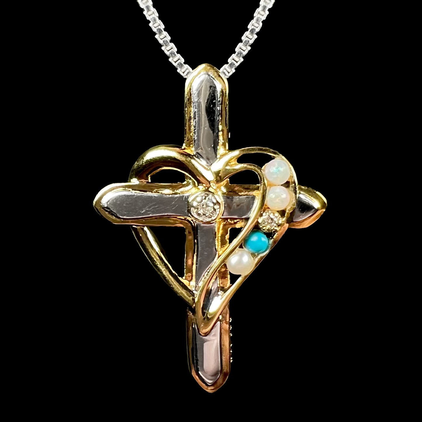 A two-tone sterling silver mother's cross necklace set with diamond, opal, turquoise, and pearl, shown close-up.